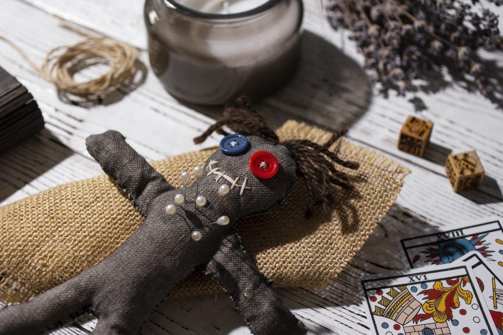 Voodoo doll with tarot cards and ritual objects representing signs of black magic